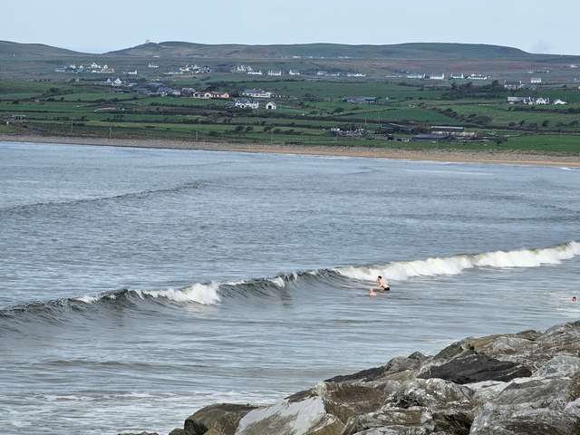 Waves breaking on the main beach as a few dippers jump into them